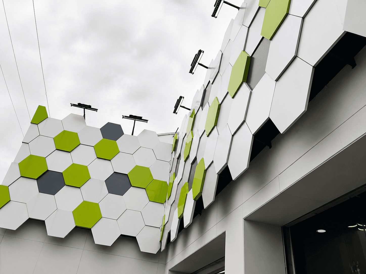 Alianza building exterior with a hexagonal white, grey, and green ACM panel facade system
