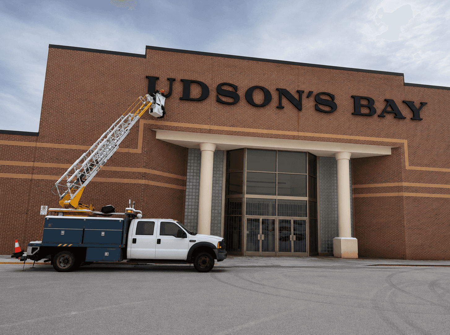 Hudson's Bay building-mounted channel letter sign with bucket truck and installer on a lift