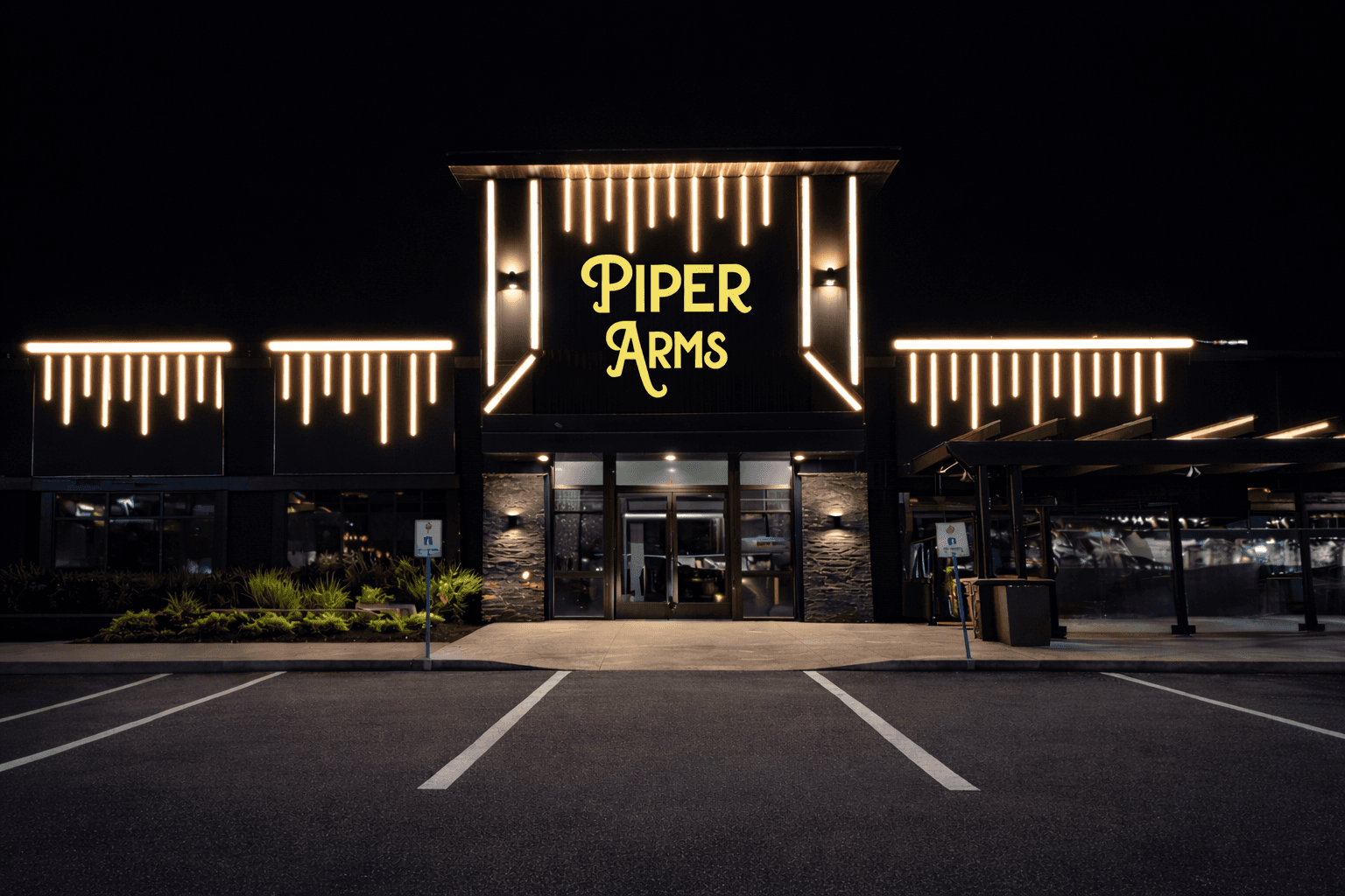 Piper Arms illuminated gold signage above a stone and black entrance at night